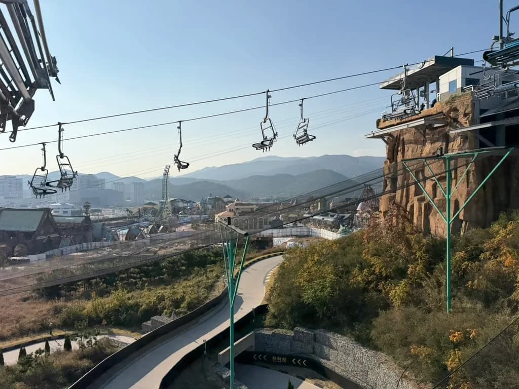 Skyline Luge 的吊椅纜車與下方的滑車車道，遠處是樂天世界與群山