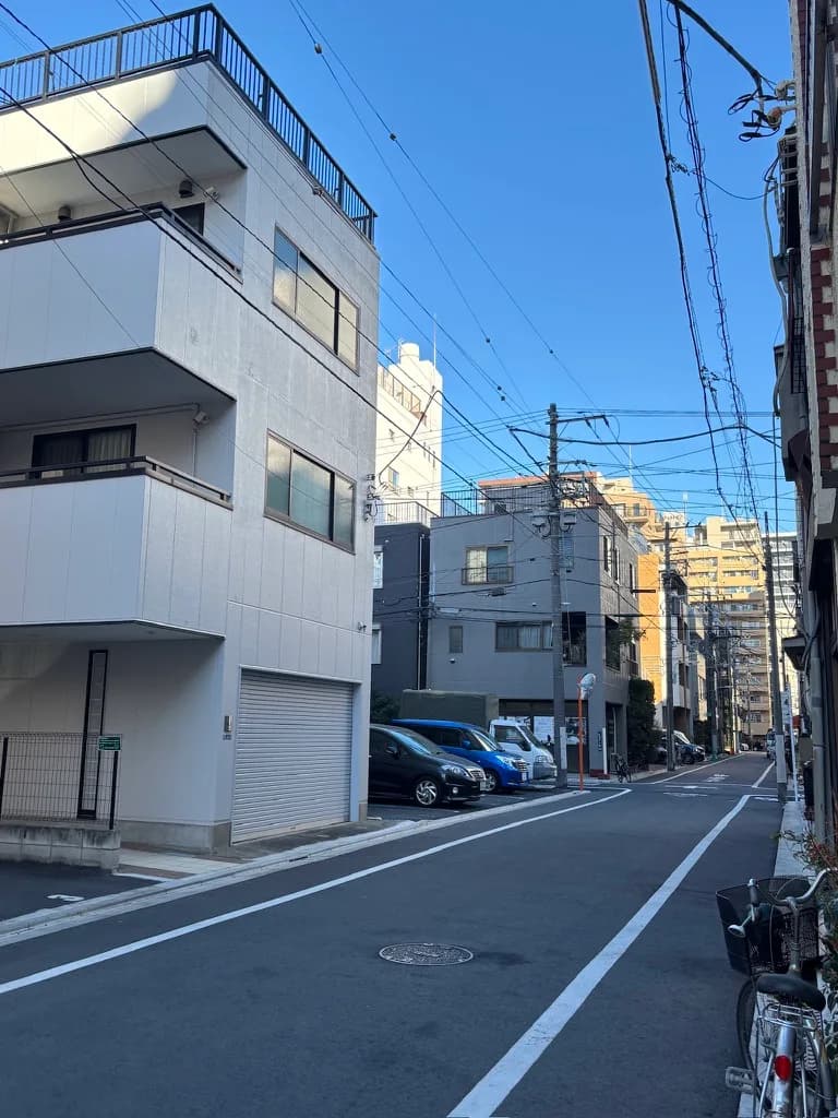 民宿外的小巷,白色的三層樓房子與停在路邊的腳踏車,天氣很好